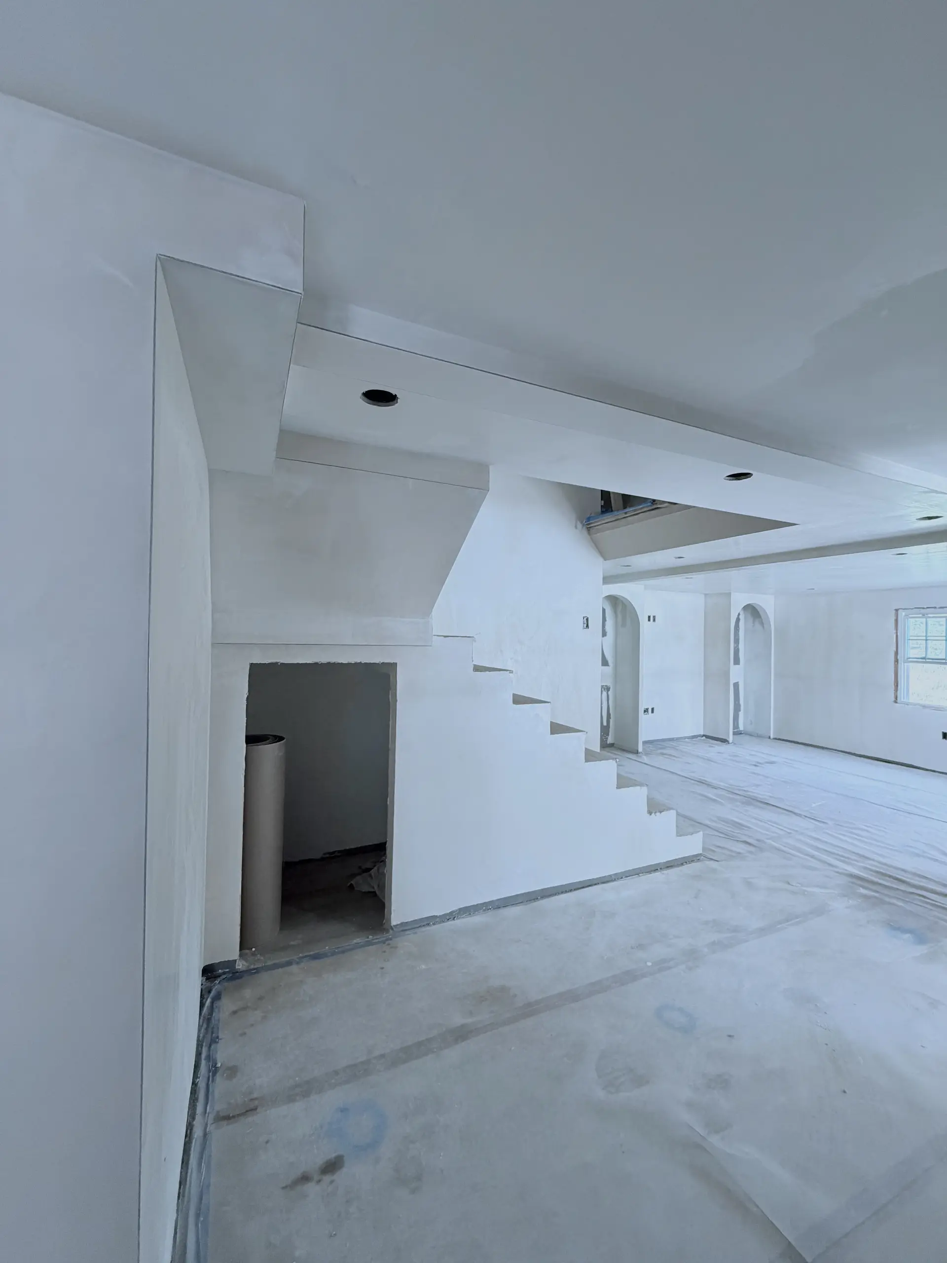 Open-plan room with newly plastered walls, ceilings, and staircase