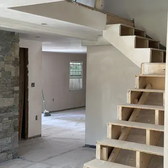 newly plastered staircase beside a stone fireplace