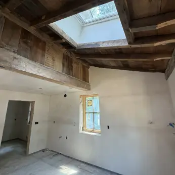 Plastered walls beneath exposed timber framing and a skylight